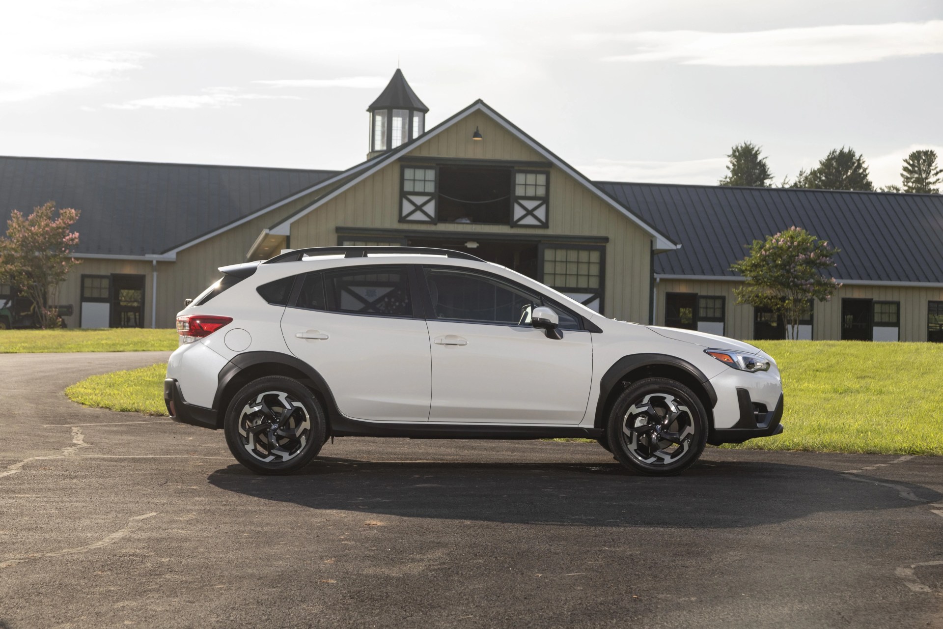 subaru crosstrek viewed from the side while parked with horse stables in the background