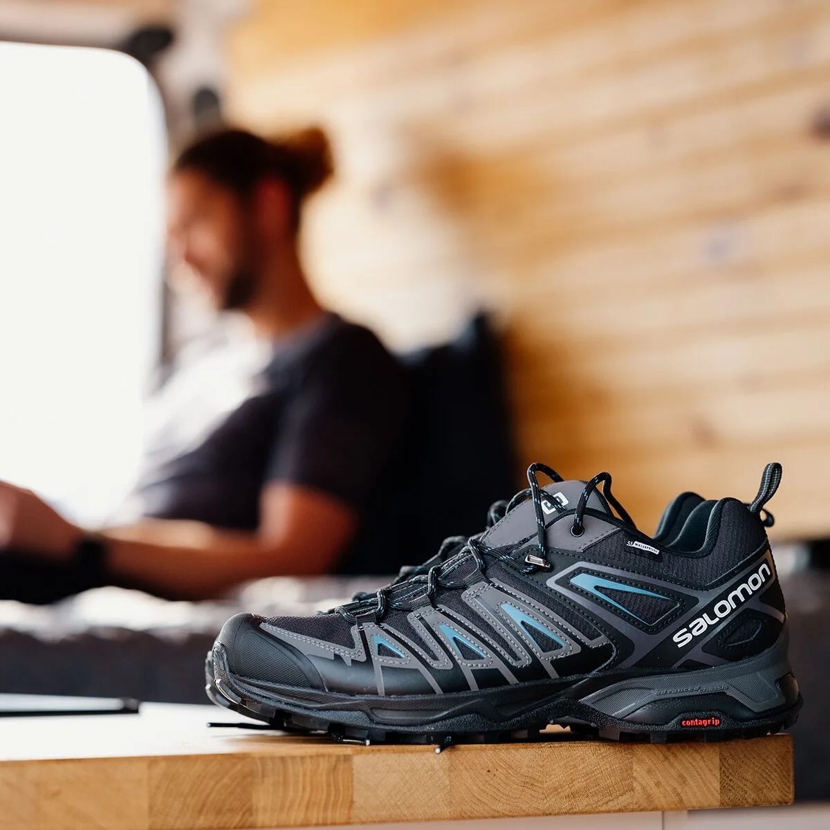 man sitting on bed with salomon sneakers in front