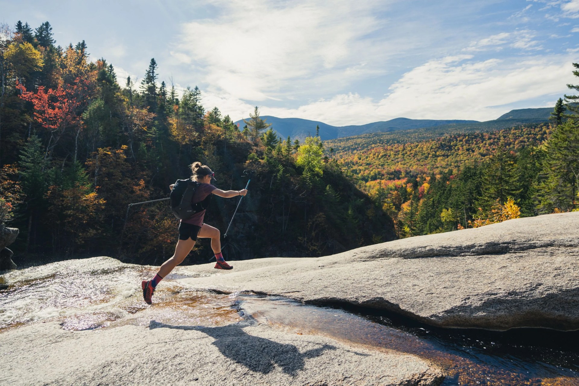 woman mountain running with a backpack and ski poles