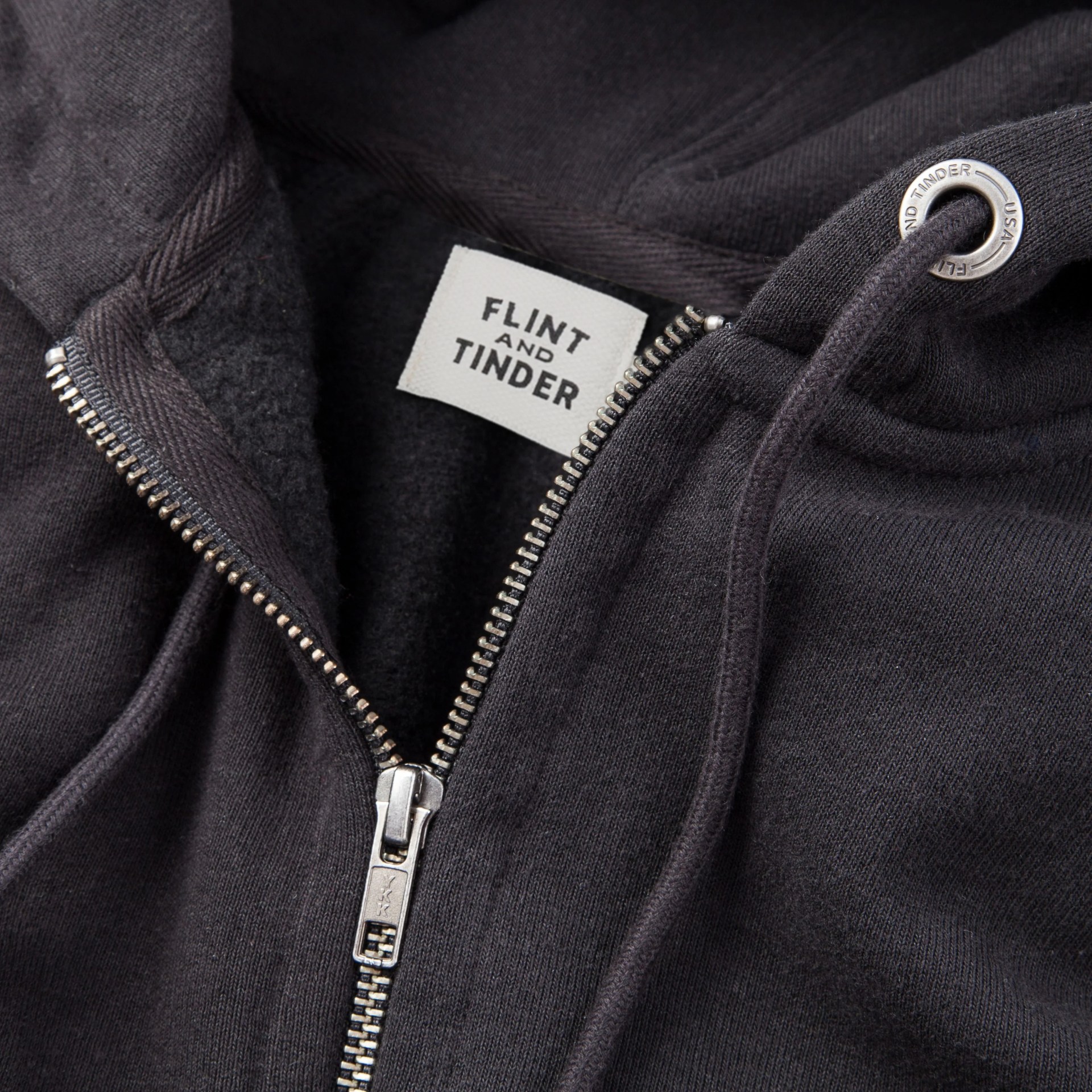 close up of the zipper on a flint and tinder black zip up hoodie