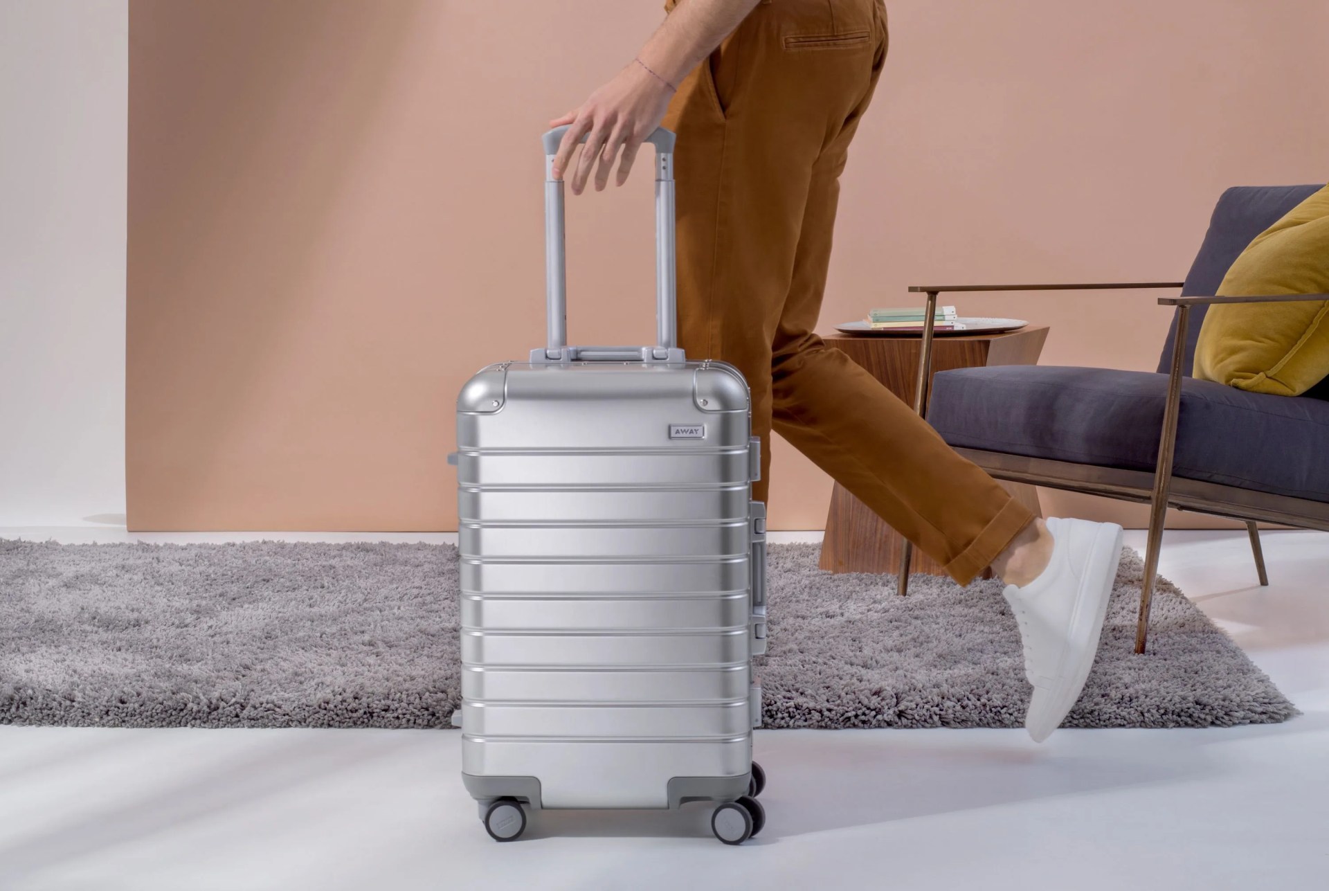 woman walking while pulling a silver away suitcase alongside her