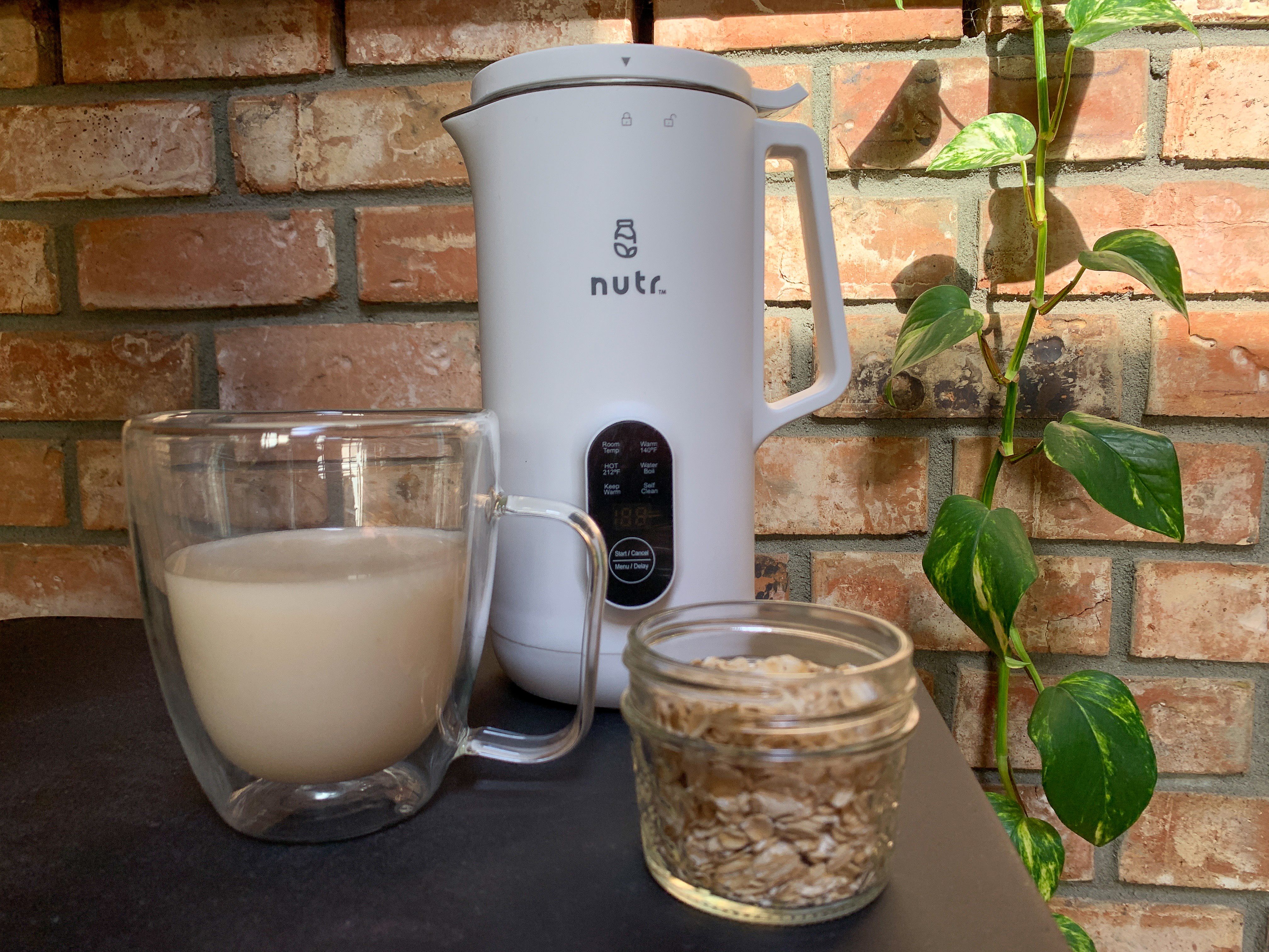 nutr machine with a cup of oat milk and jar of oats