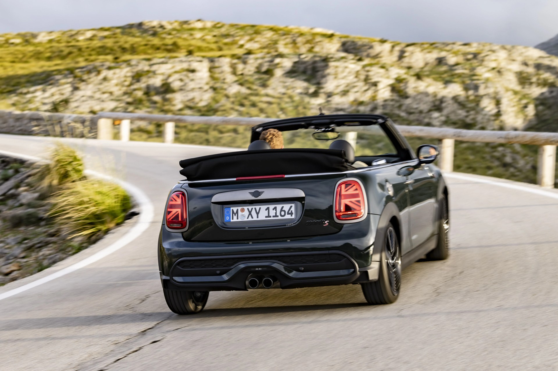 mini convertible from the rear driving up a mountain highway