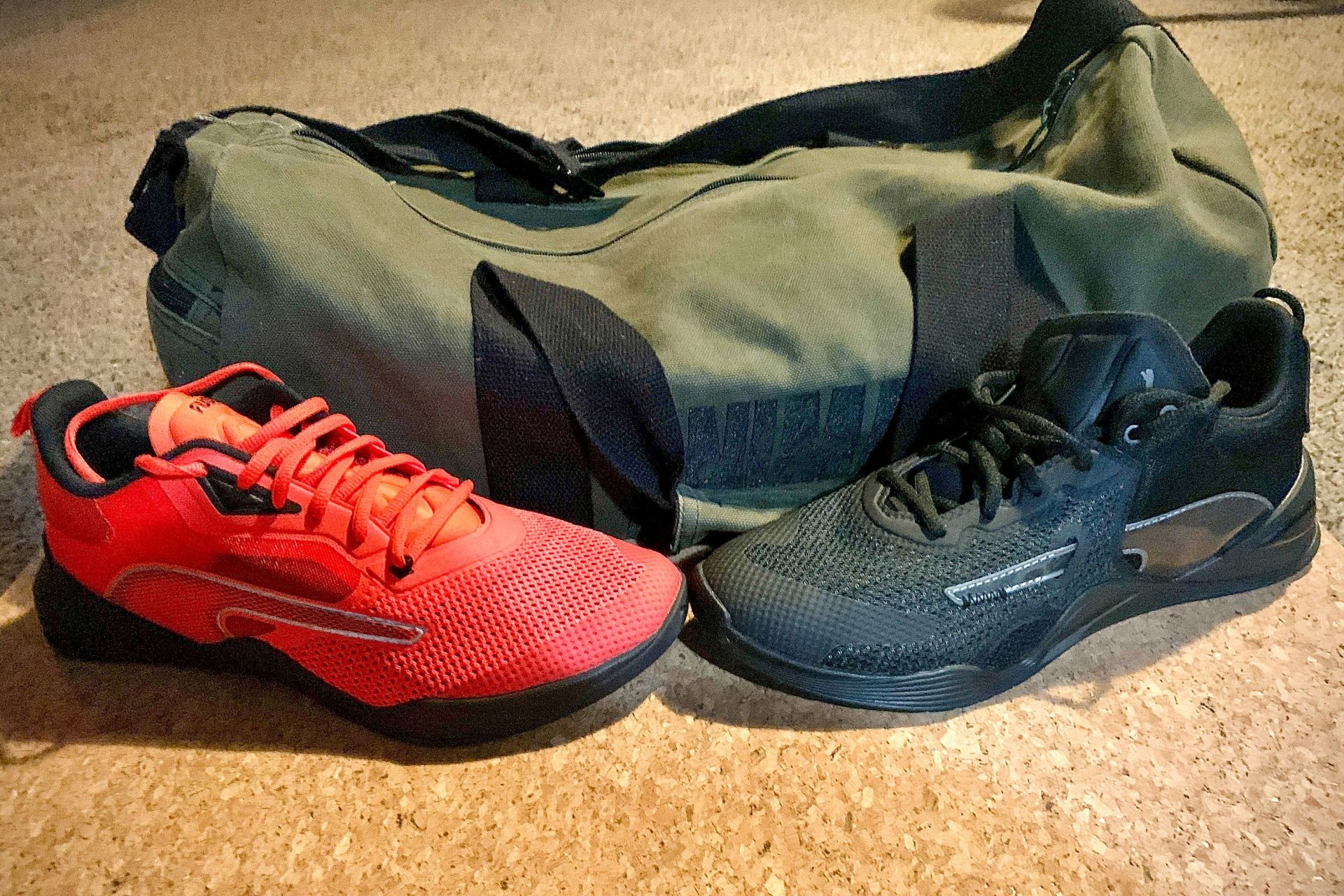 red and black puma fuse shoes next to a green duffel bag