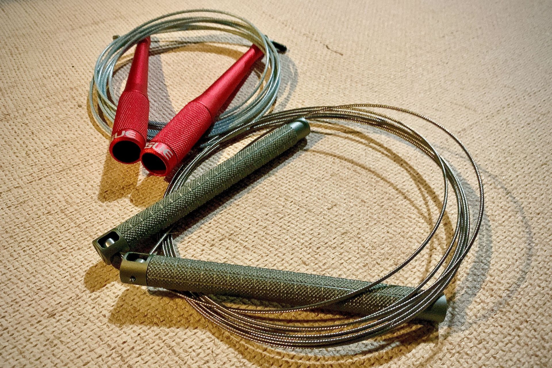 two cable jump ropes curled up on a carpet