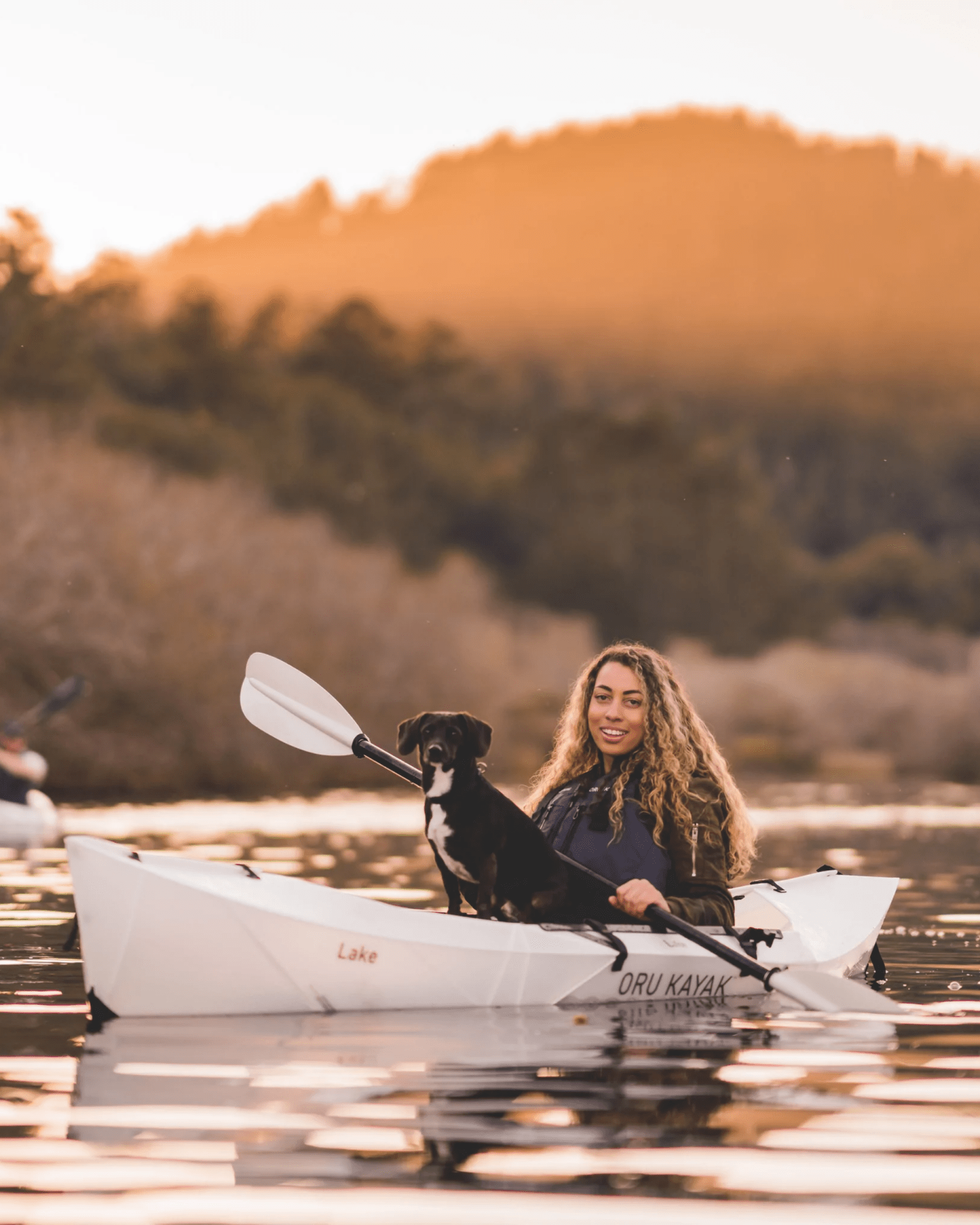 a person and dog in a oru kayak on the water