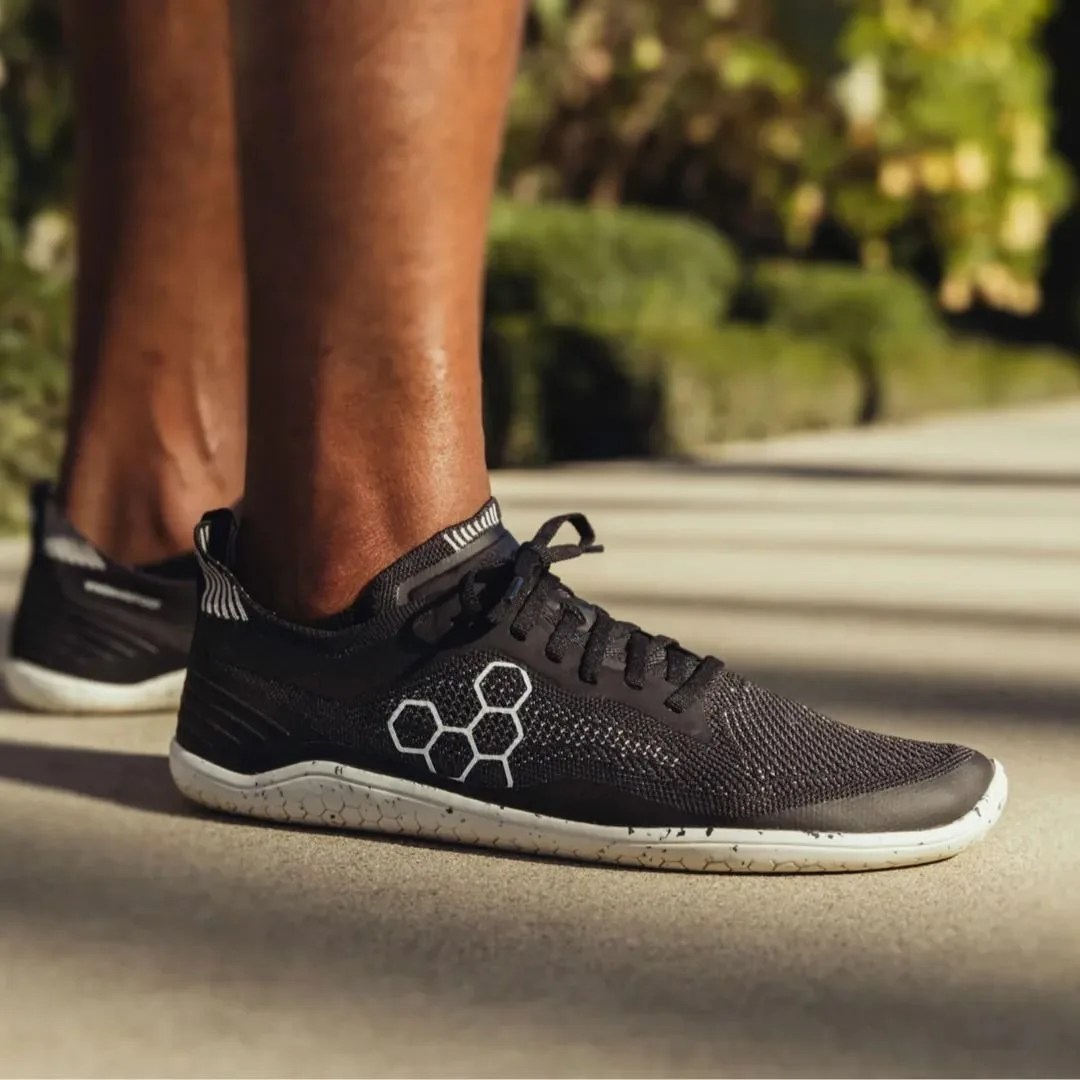 a man standing on a sidewalk in barefoot running shoes