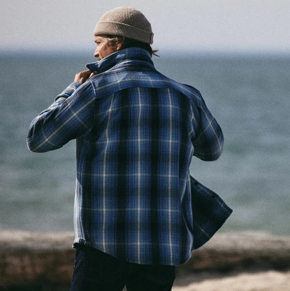 a man wearing a flannel shirt at the beach