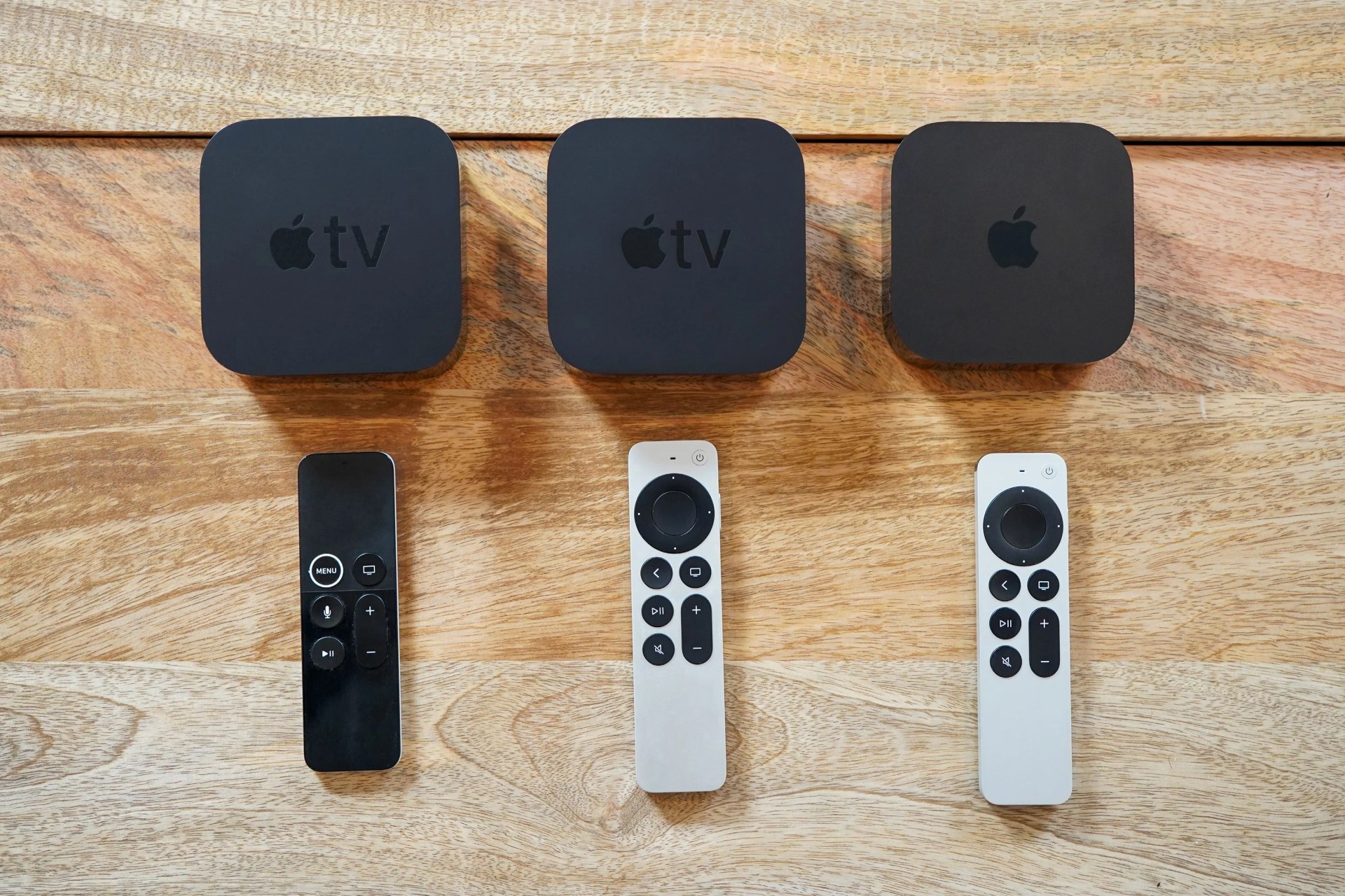 3 apple tv's with remotes on a table