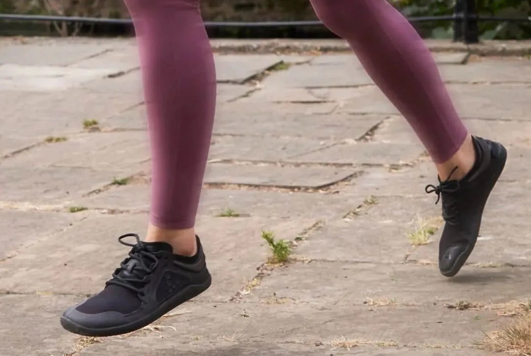 a woman running in barefoot running shoes