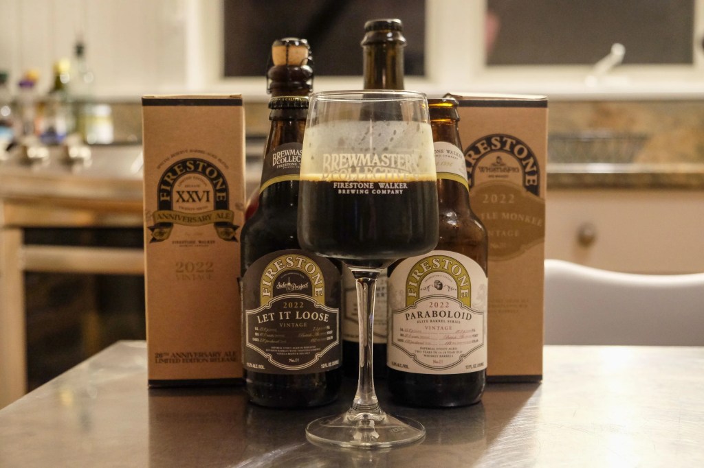 three bottles of firestone walker beer with a half full glass sitting on a table