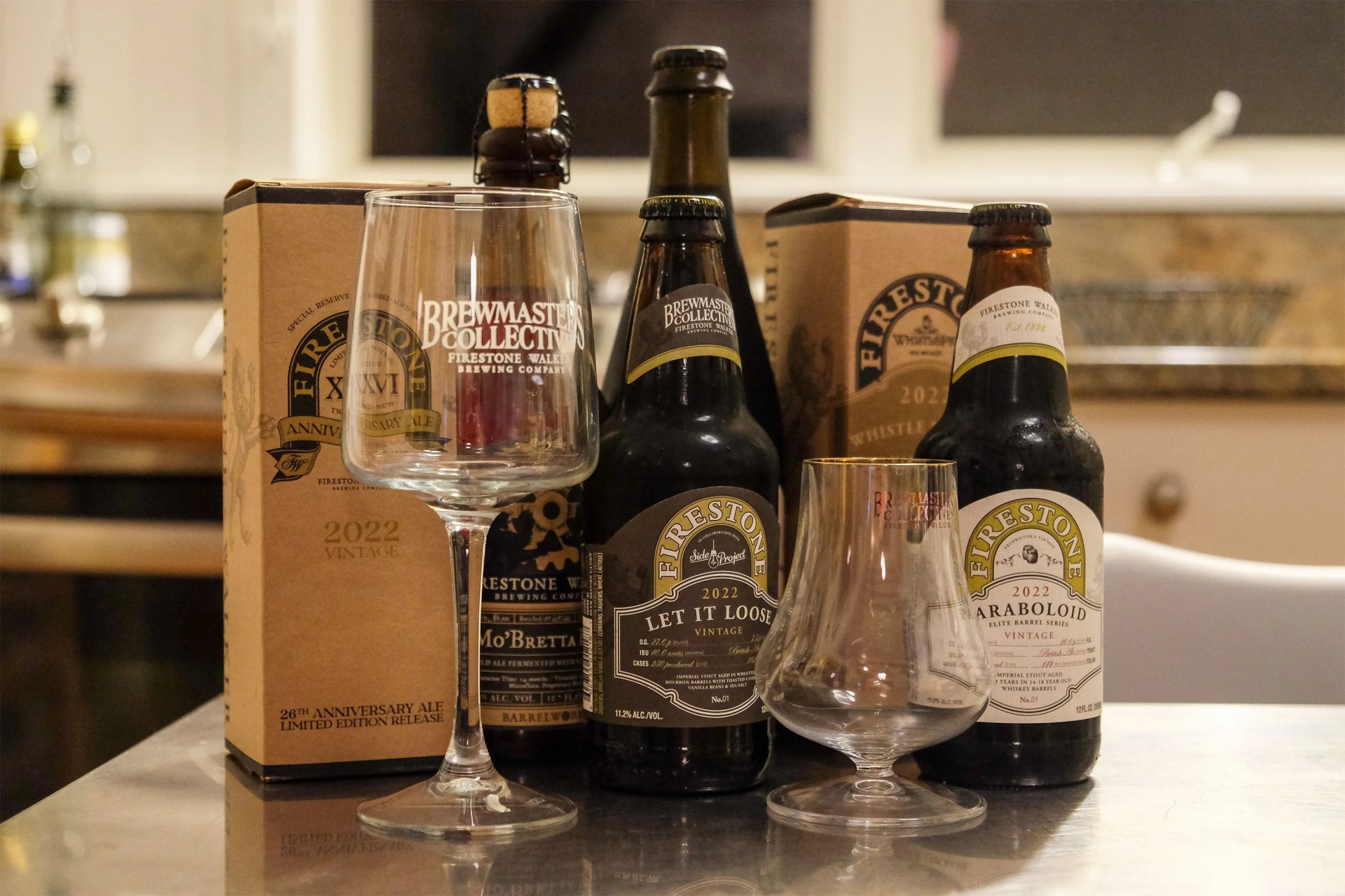 a collection of firestone beer bottles and 2 beer glasses on a table
