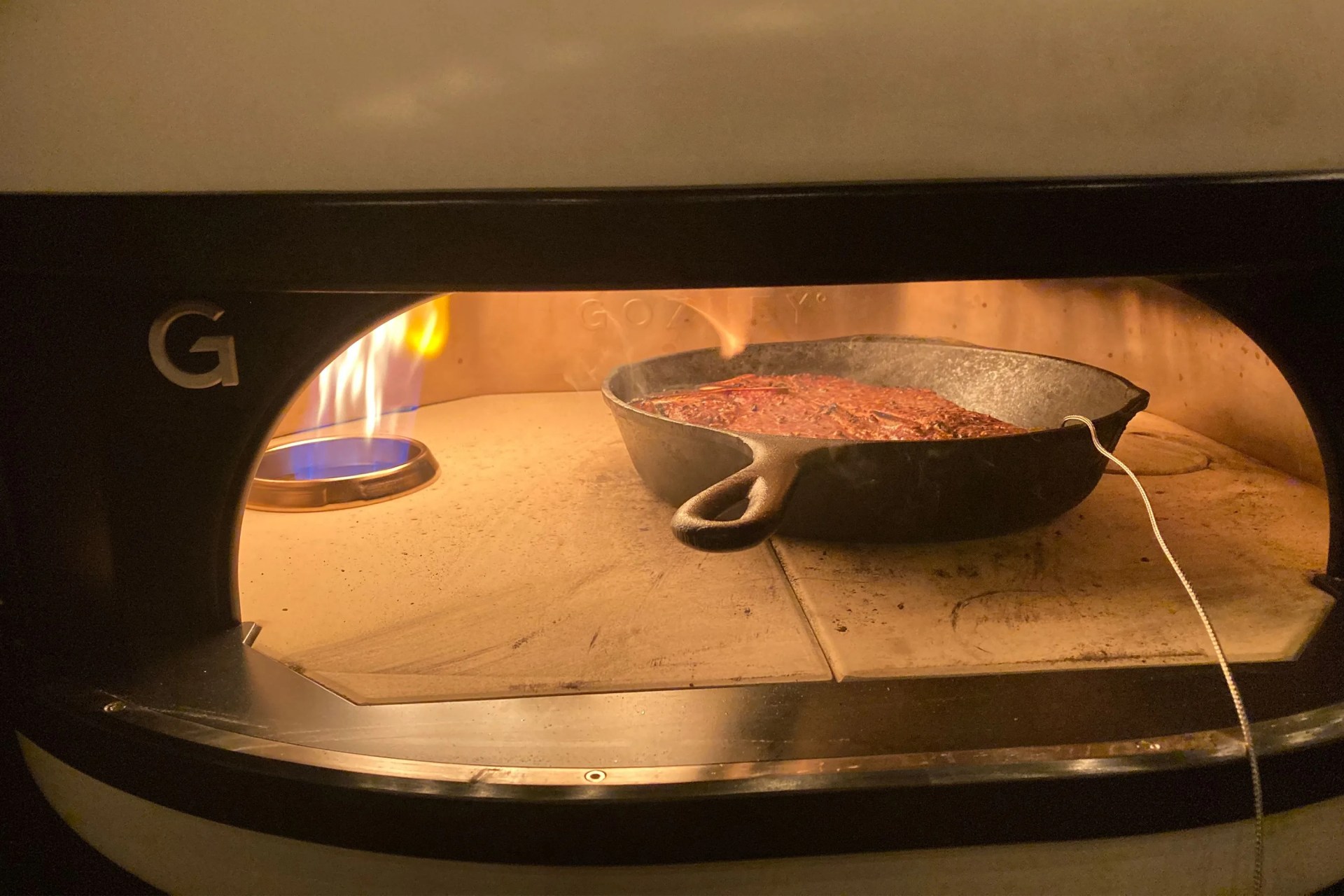 a steak cooking in a gozney dome pizza oven