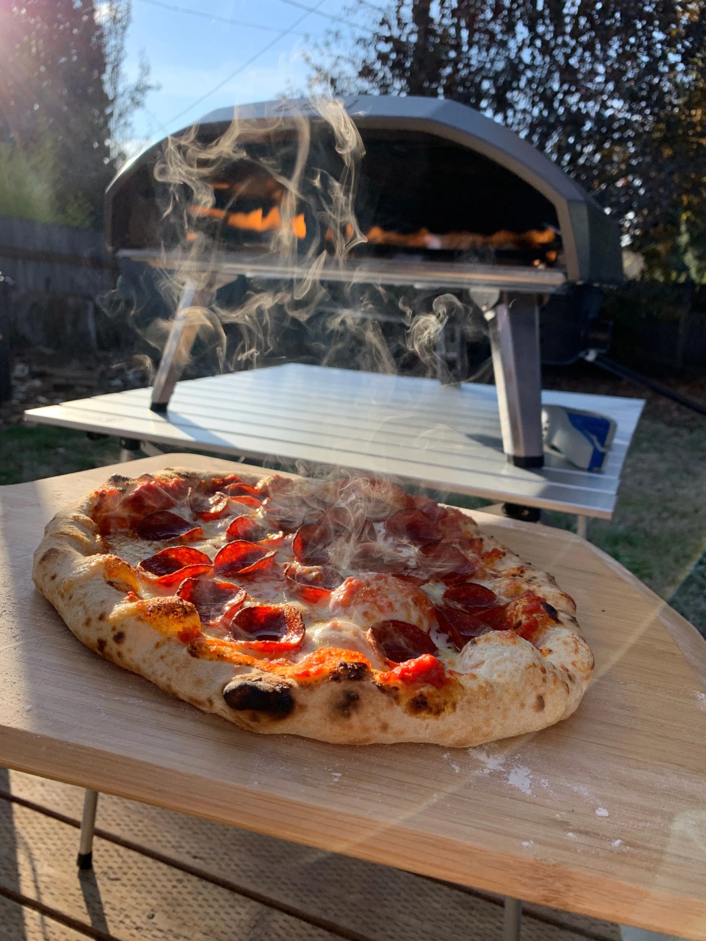 a hot pizza cooling in front of an ooni pizza oven