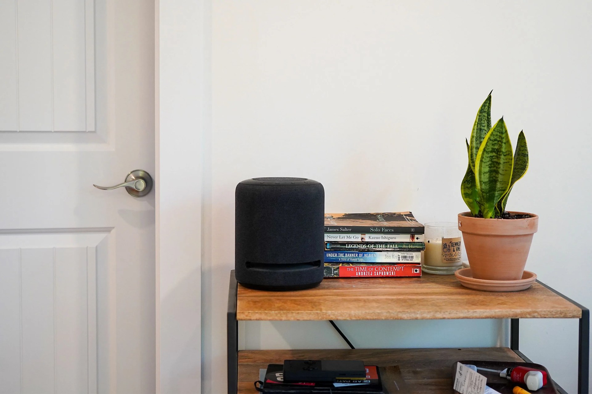 an amazon speaker sitting on a side table next to books