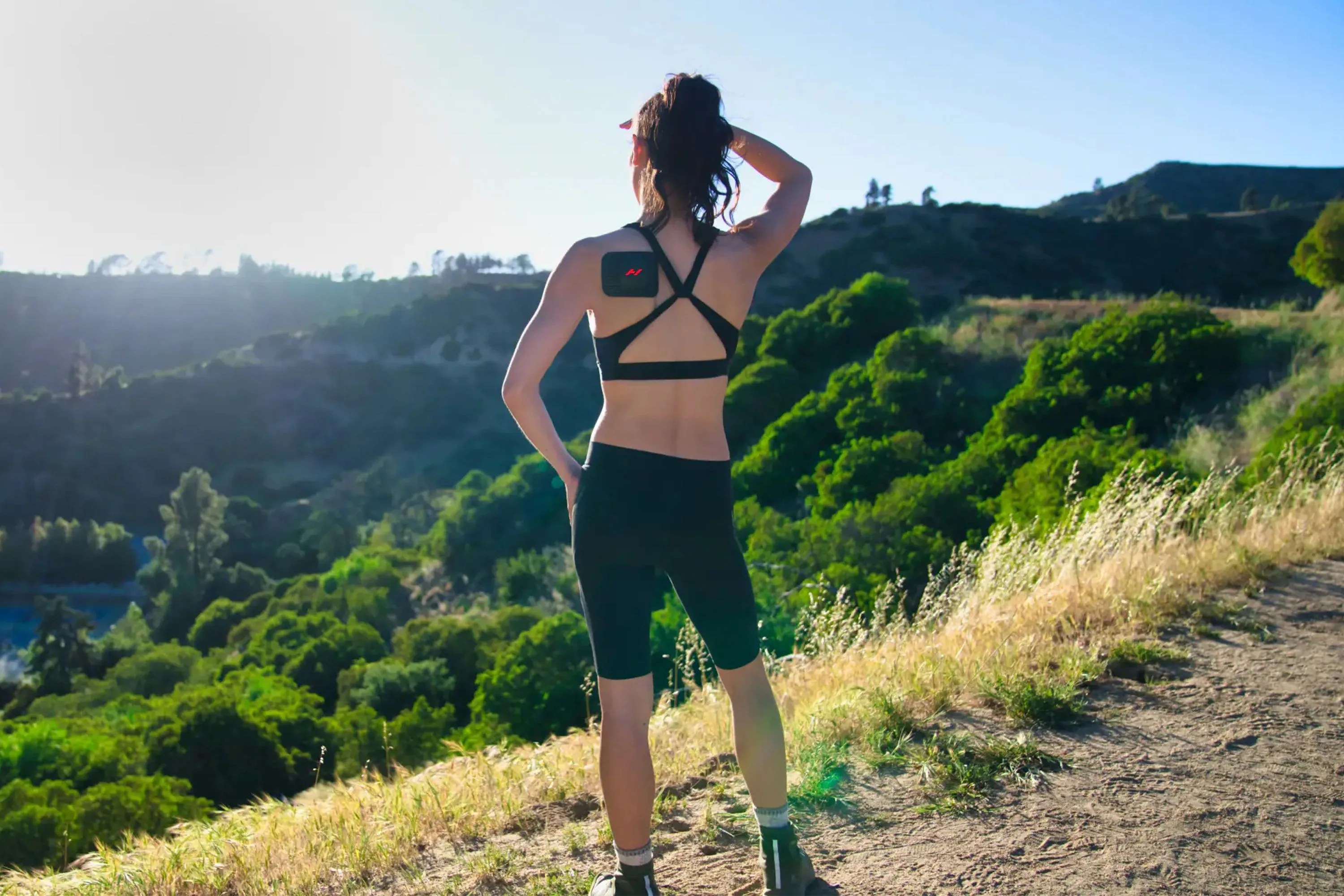 woman running a trail while wearing the hyperice go on her shoulder