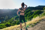 woman running a trail while wearing the hyperice go on her shoulder