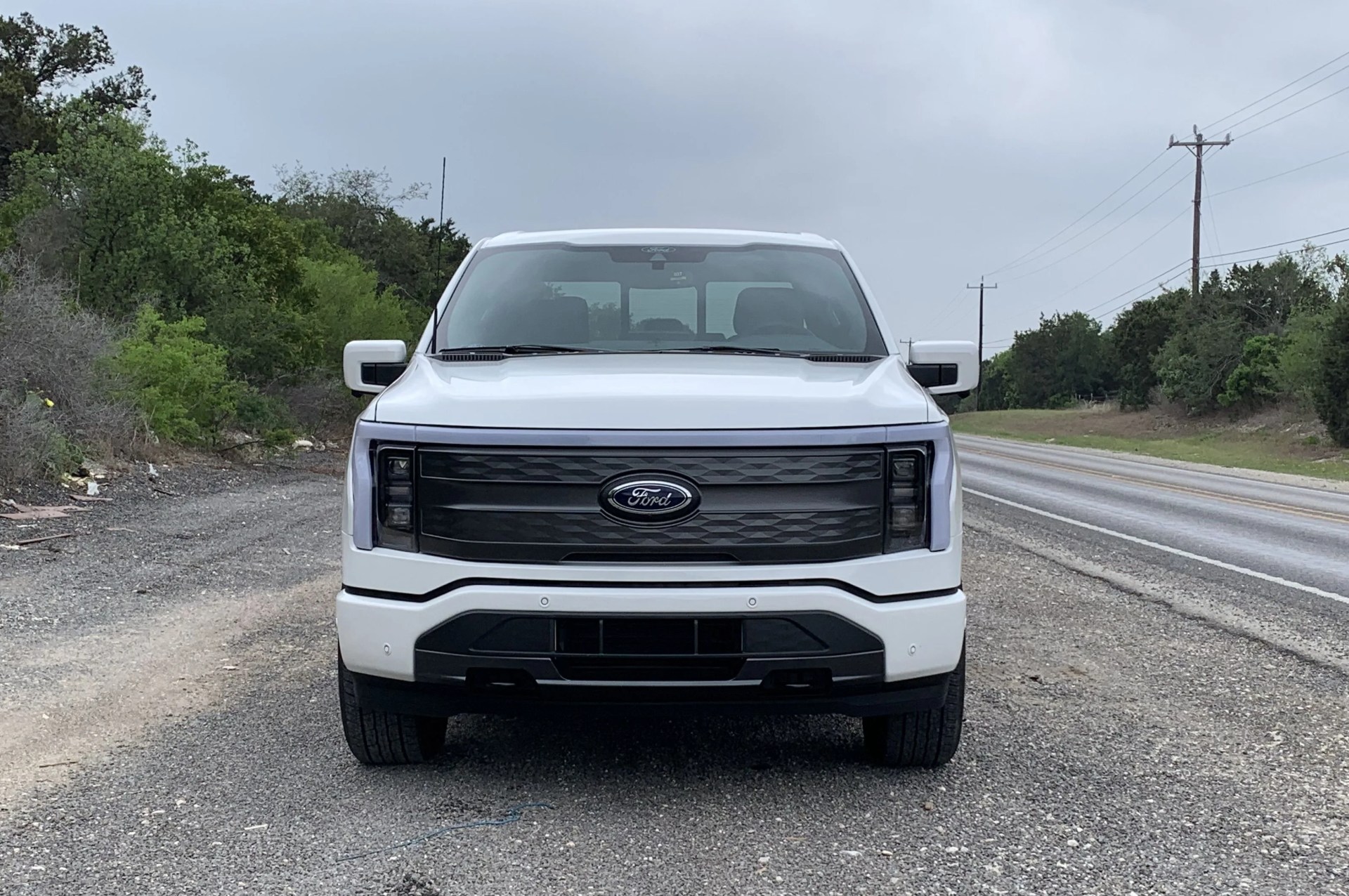 ford f 150 lightning in white on the side of a two lane highway in texas