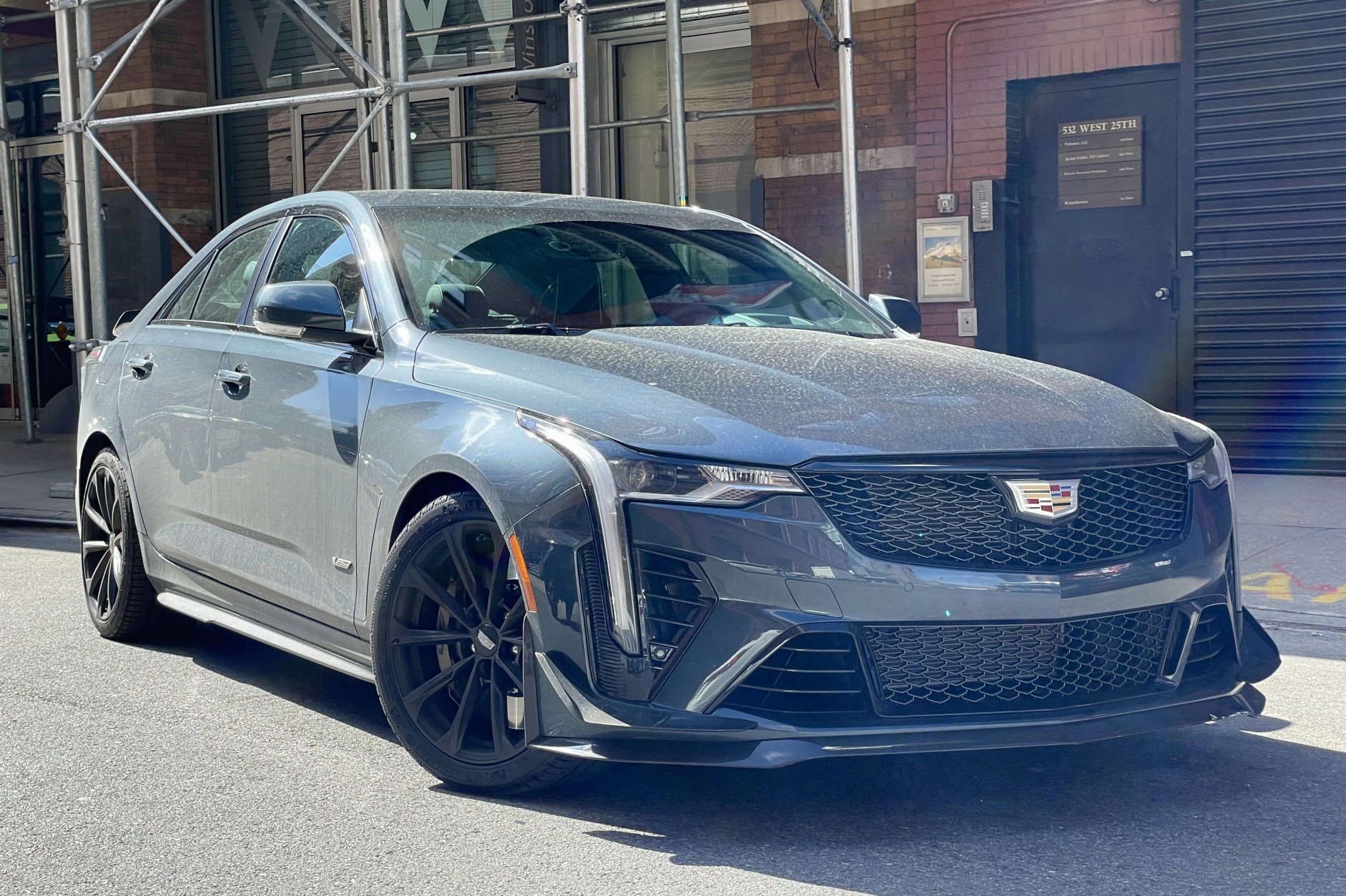 2022 cadillac ct4 v blackwing sedan in blue gray in front of some scaffolding in a washed out picture