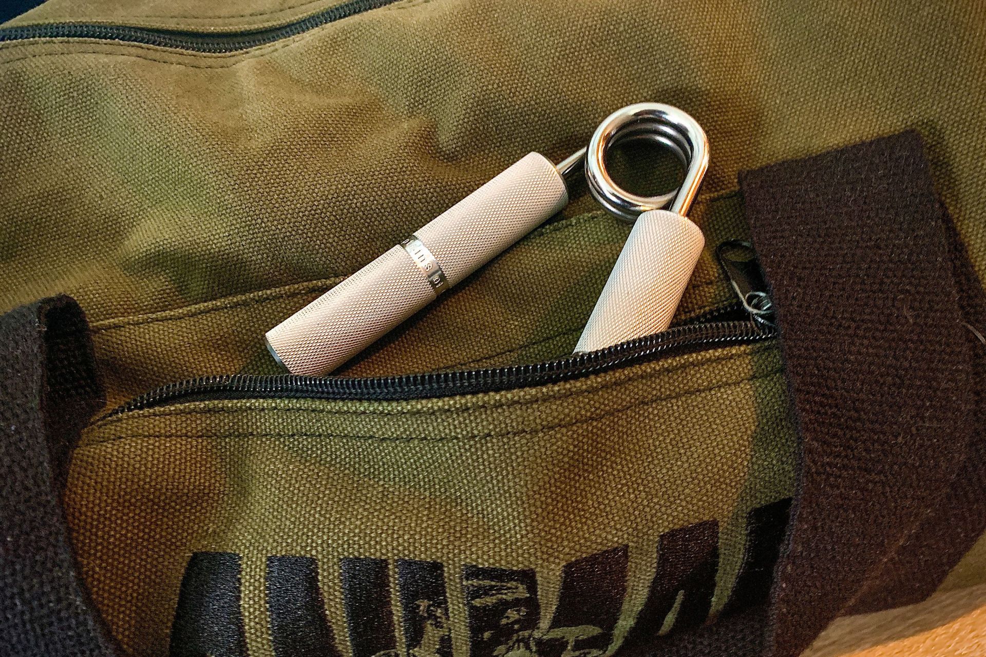 ironmind's captains of crush gripper in the front pocket of a duffel bag