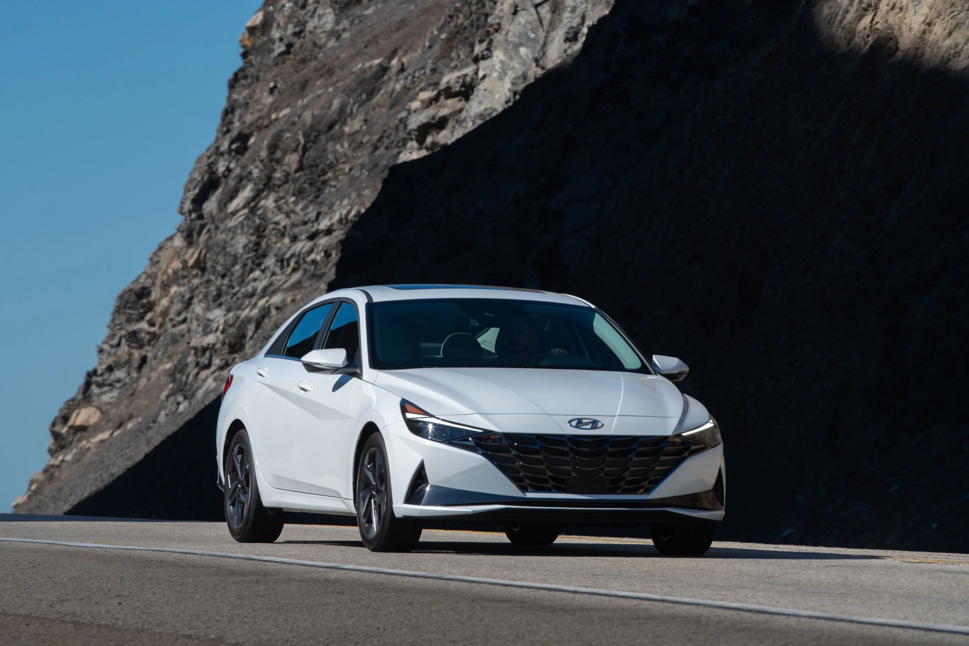 white hyundai elantra parked next to a rocky cliff face