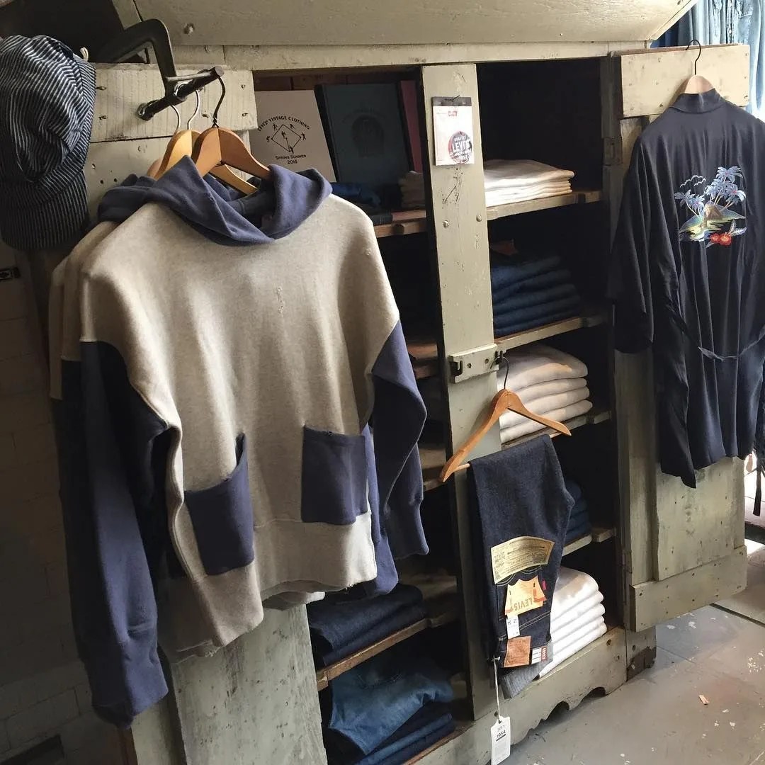 a patch pocket hoodie handing next to shelves of folded jeans