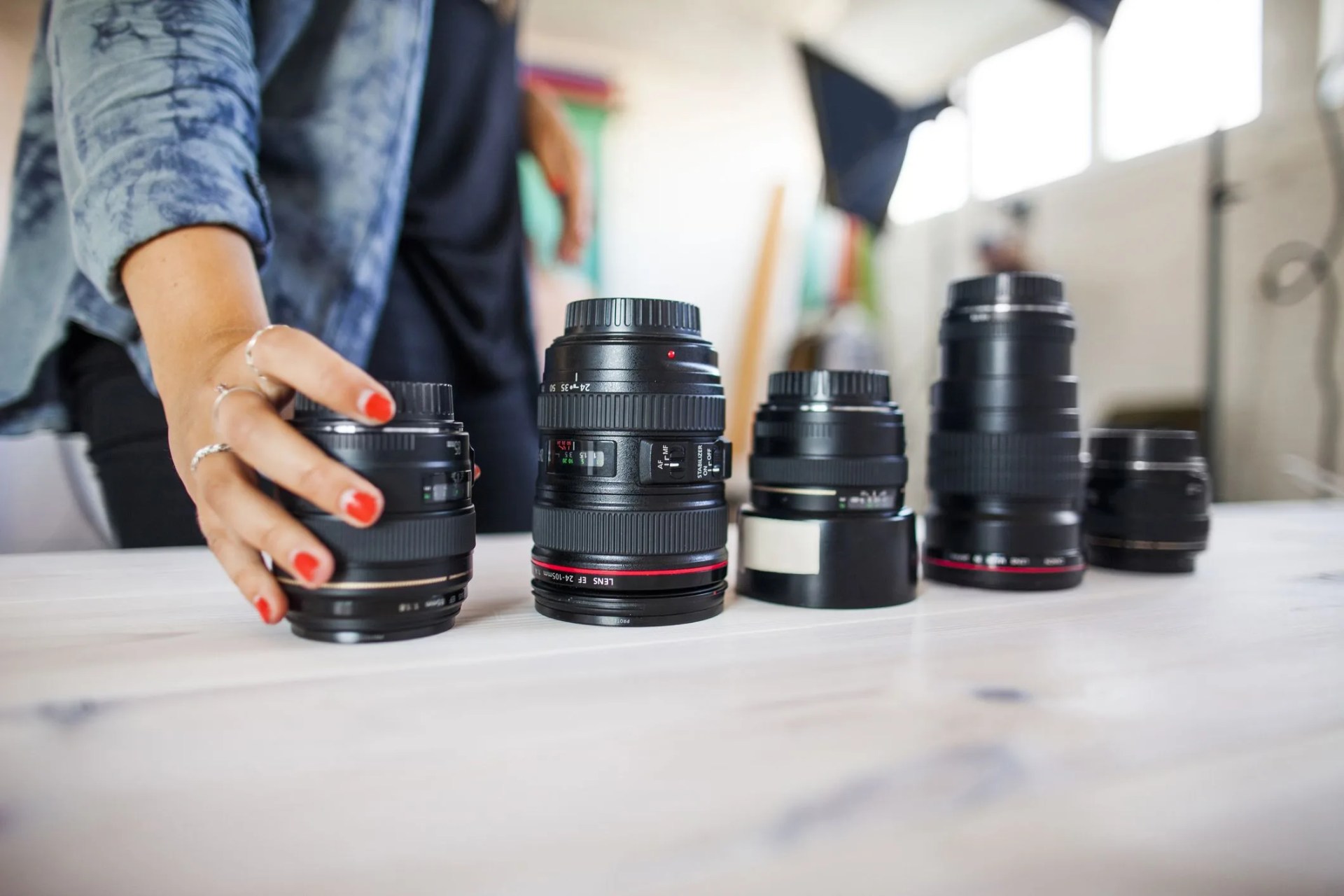 midsection of photo assistant arranging various lenses on table in studio