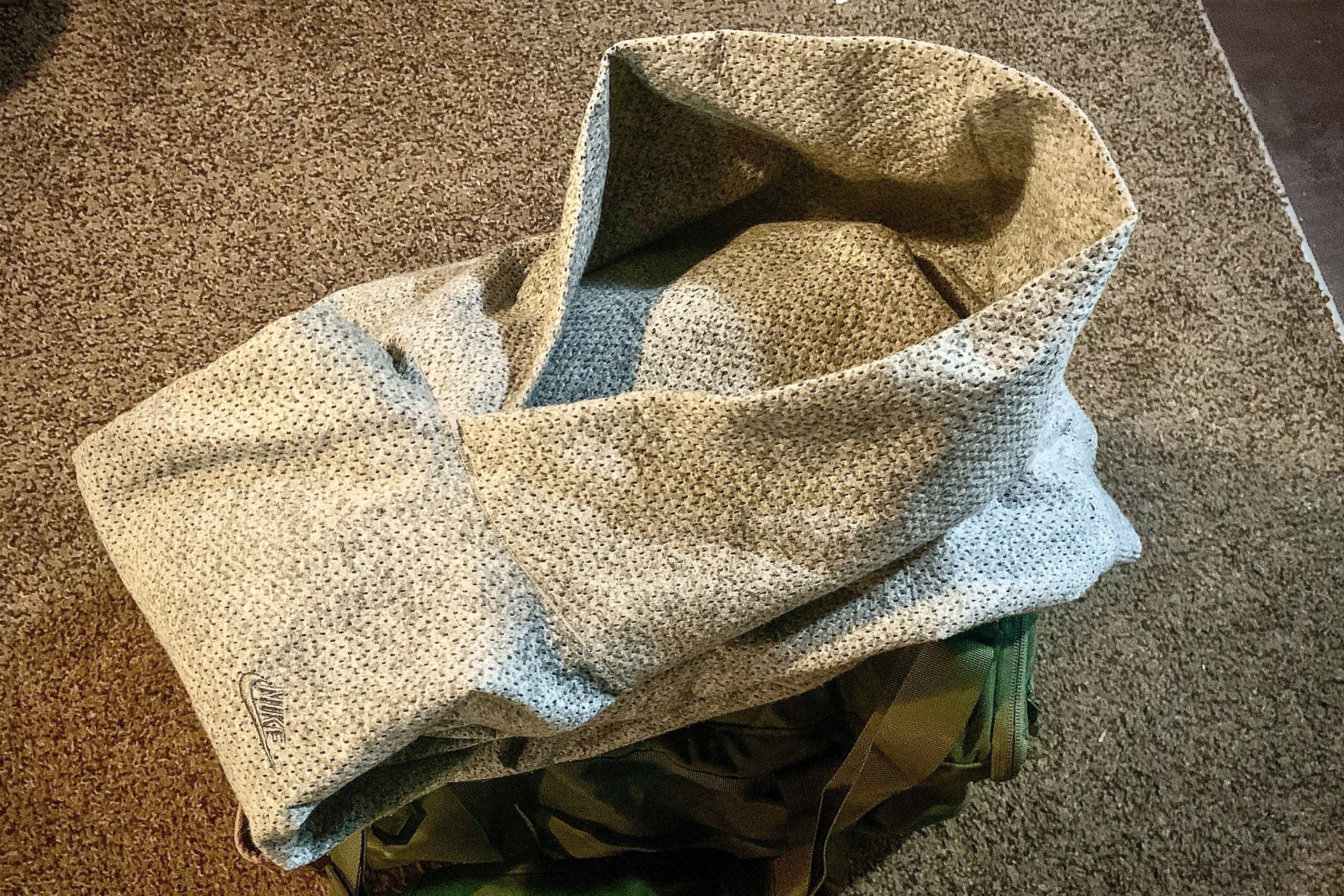 a folded nike hoodie on top of a green duffel bag