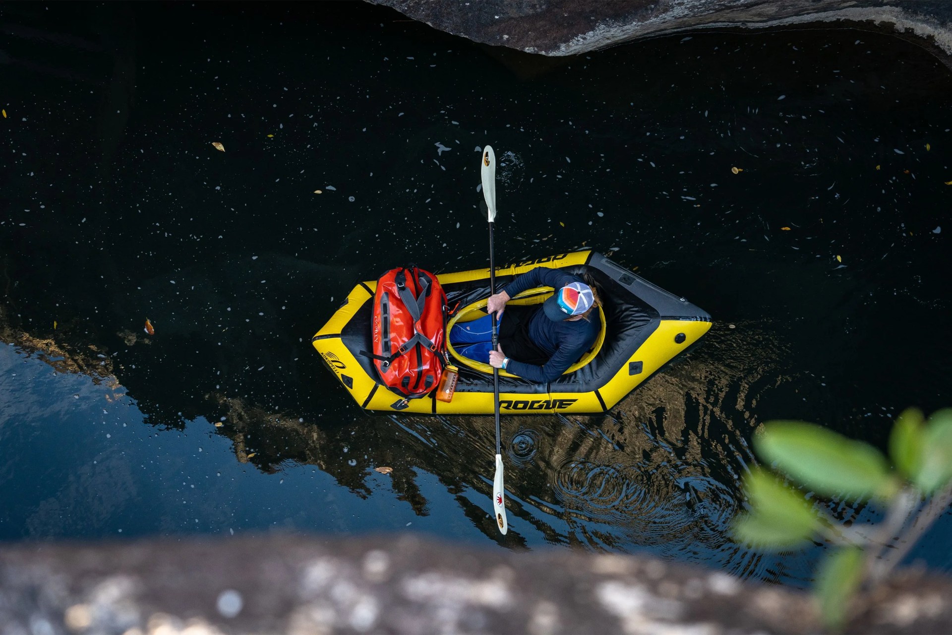 a man in an inflatable kayak with an osprey duffel bag