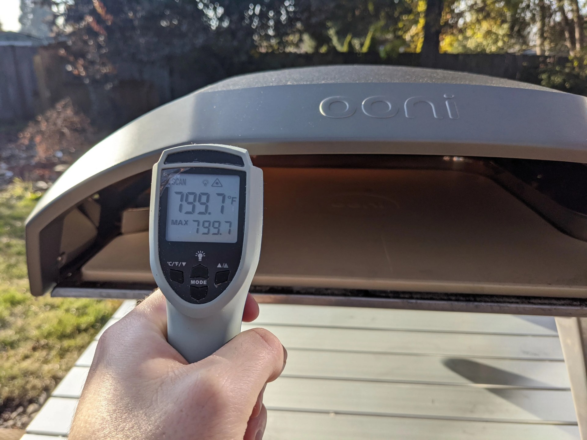 a person with a thermometer taking the temperature of an ooni pizza oven