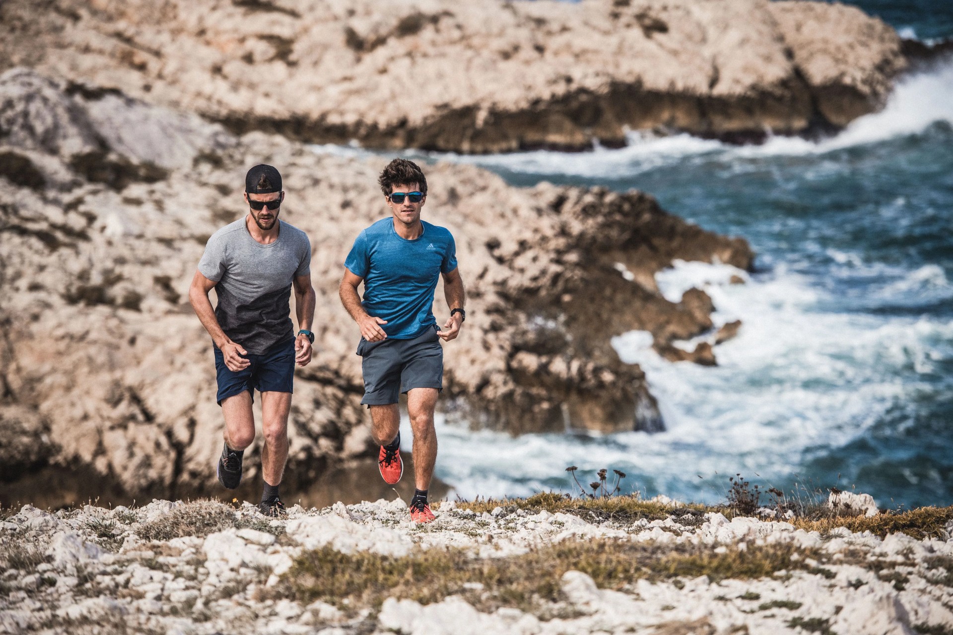two men running along coastline wearing julbo sunglasses