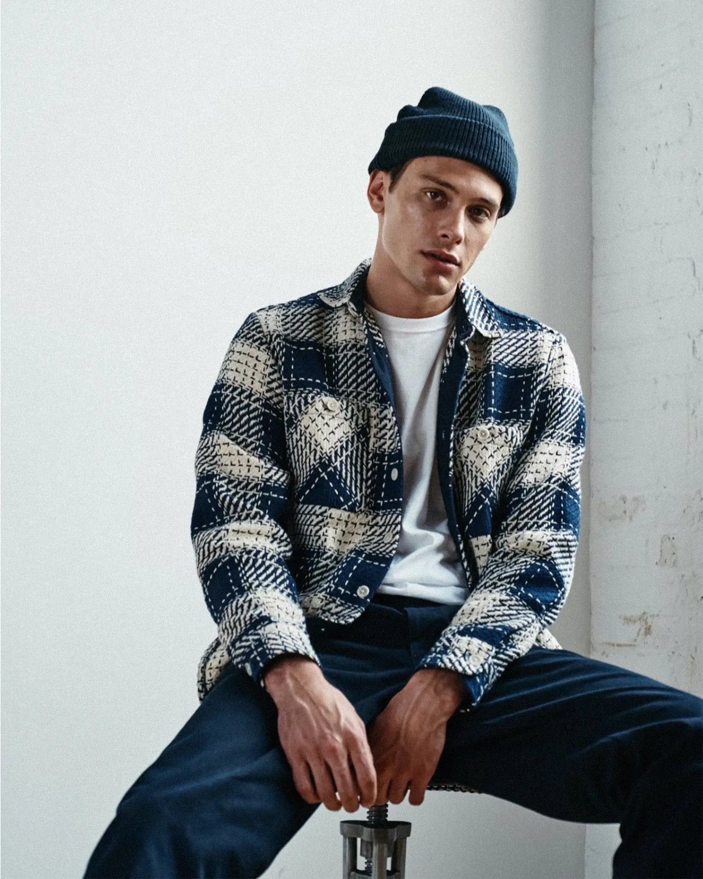 a man wearing a wax london flannel while sitting on a stool