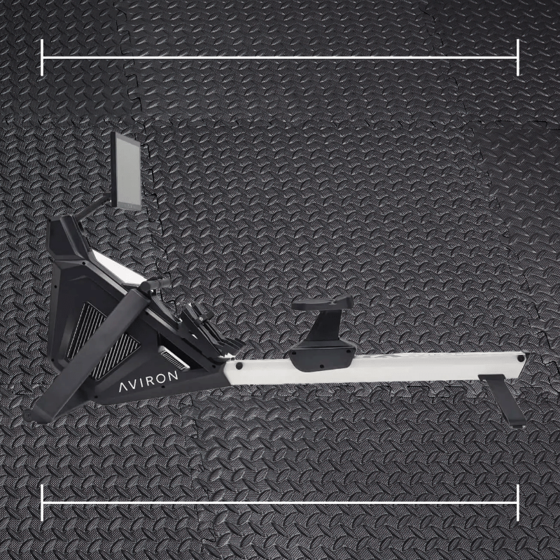 a black aviron rowing machine laid over a photo of black rubber gym flooring