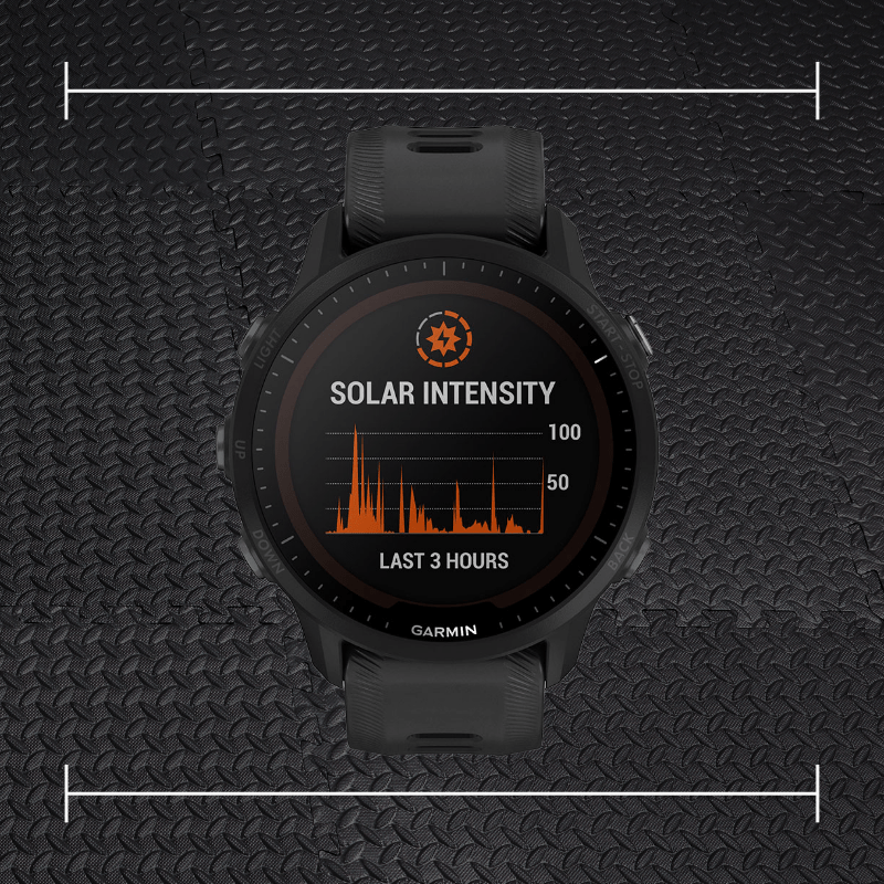 a black garmin forerunner watch laid on top a photo of black rubber gym flooring