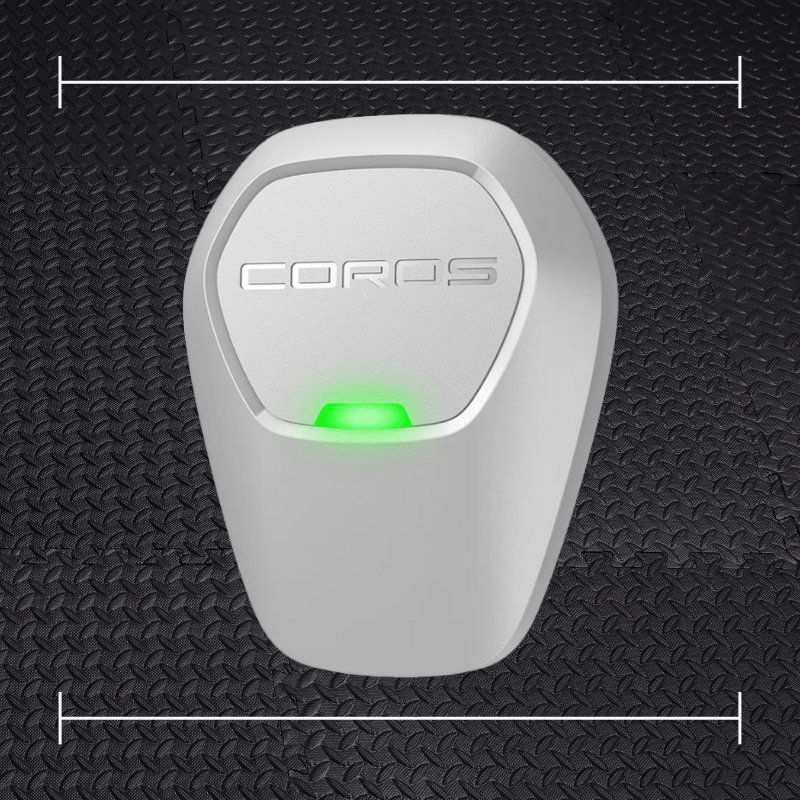 a white coros pod laid on top a photo of black rubber gym flooring