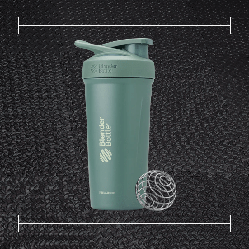 a green blender bottle laid on top a photo of black rubber gym flooring