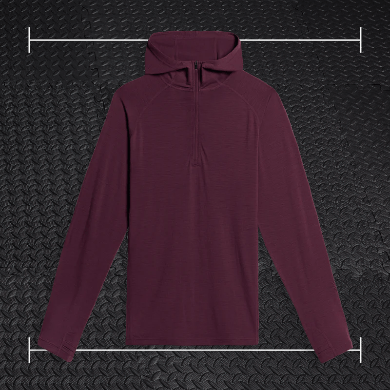 a maroon ibex three quarter zip hoodies laid over top a photo of black rubber gym flooring