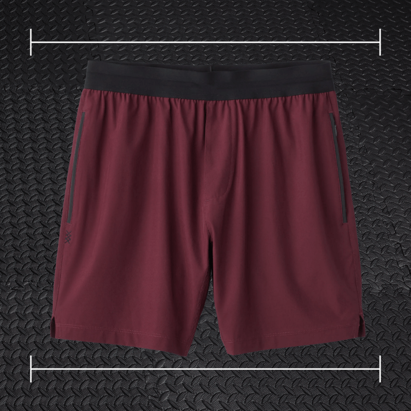 Red Rhone shorts laid over top a photo of black rubber gym flooring