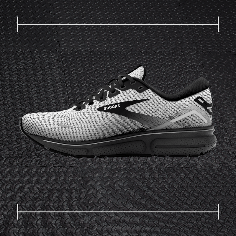 a black and grey brooks shoe laid over top a photo of black rubber gym flooring