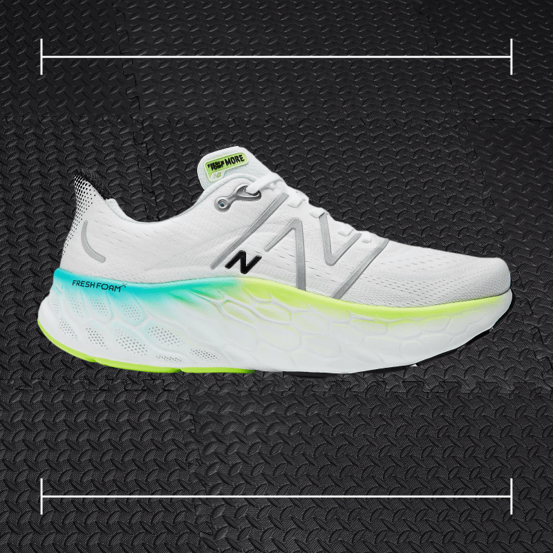 white new balance shoe with blue and green accents laid over top a photo of black rubber gym flooring