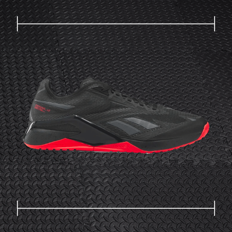 black reebok shoes with red accents laid over top a photo of black rubber gym flooring