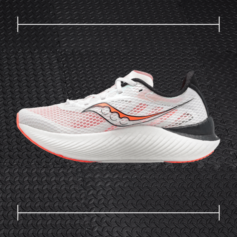 white saucony shoes with black and orange accents laid over top a photo of black rubber gym flooring