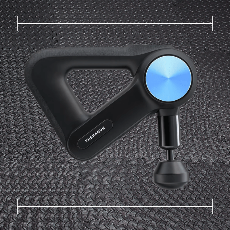 black Theragun massage gun with blue accent laid over top a photo of black rubber gym flooring