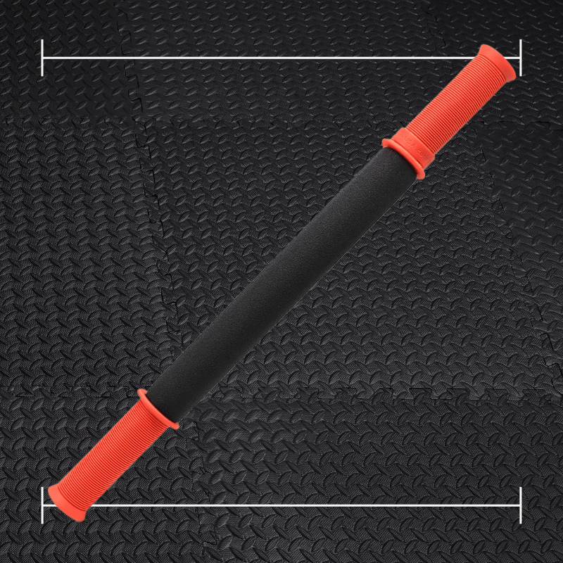 black tiger tail massage stick with orange accents laid over top a photo of black rubber gym flooring