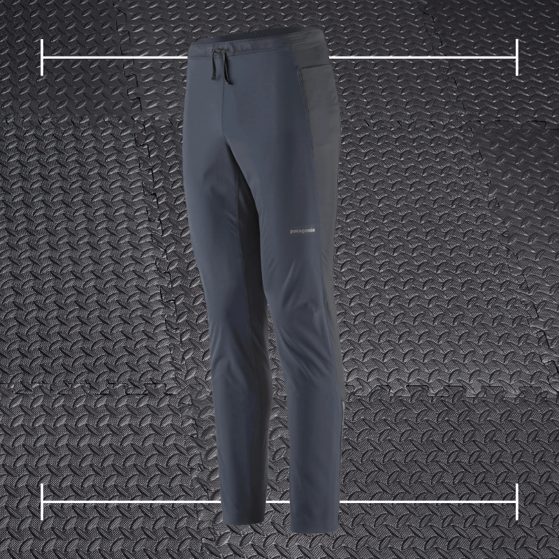 black patagonia pants laid over top a photo of black rubber gym flooring