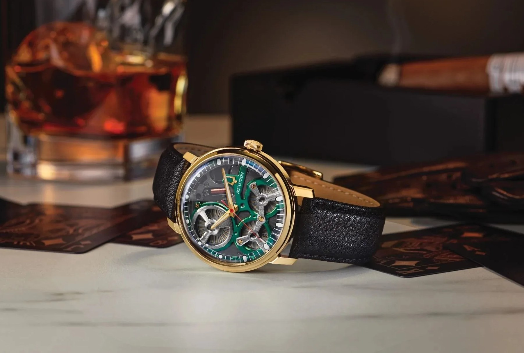 an accutron watch on a table with a whiskey glass and cigar