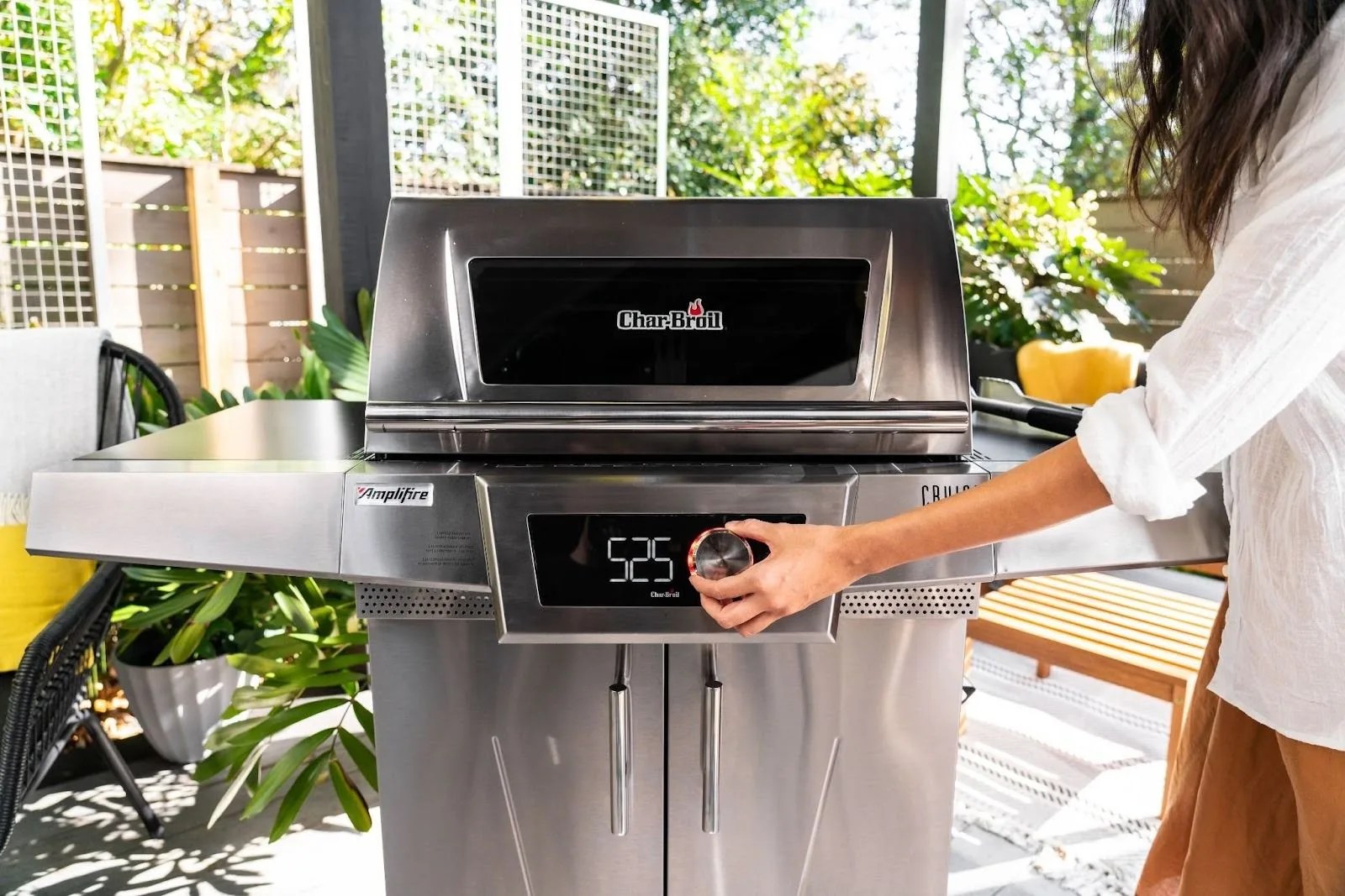 a woman turning on a char broil grill