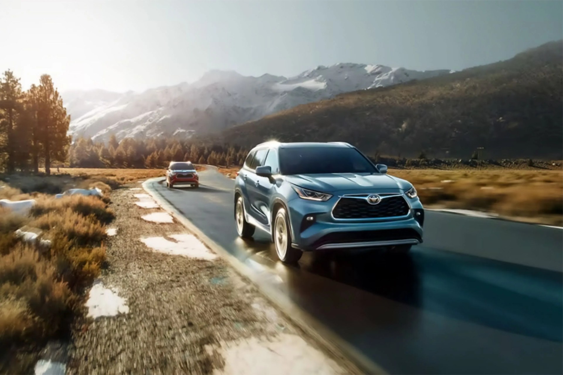 two cars on a highway with a snowy mountain background