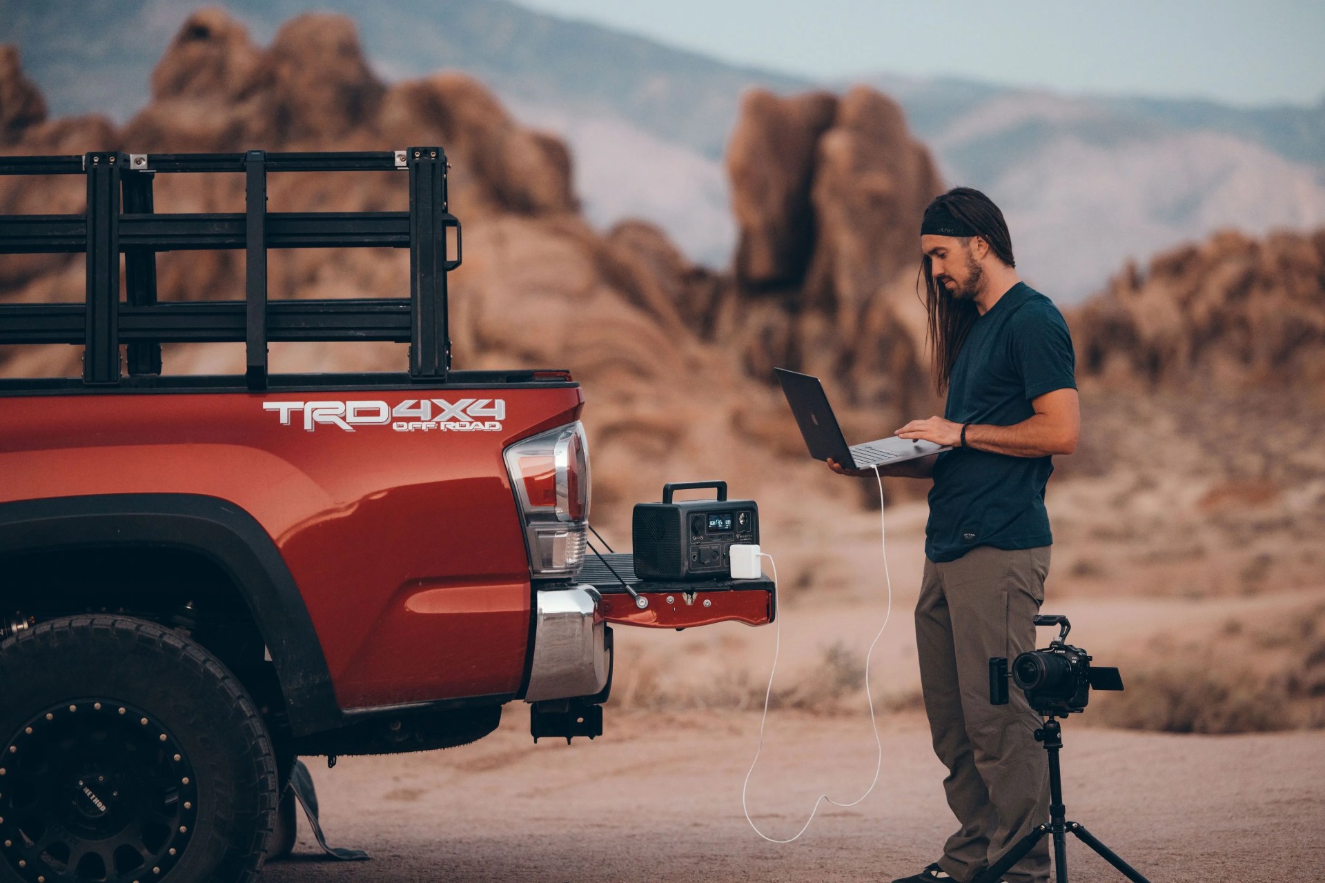 man using bluetti eb3a portable power station to charge laptop on back of car