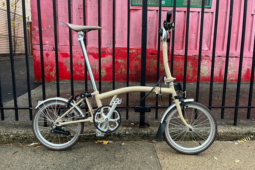a brompton c line explore bike next to a fence